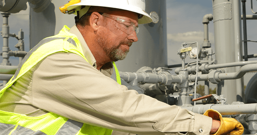 Utility worker wearing safety glasses working on a natural gas pipeline.