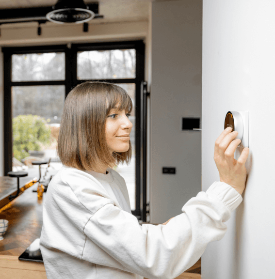 woman adjust thermostat 567x576